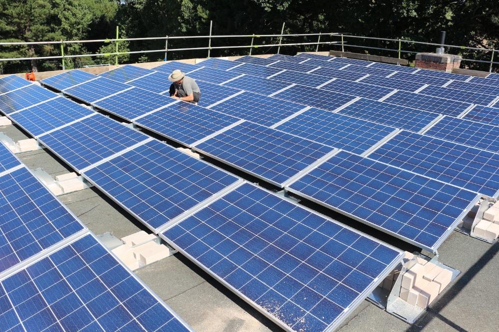 Brightspark employee working in the sun wiring up the solar PV installation on the roof of Pheonix St Peters Academy